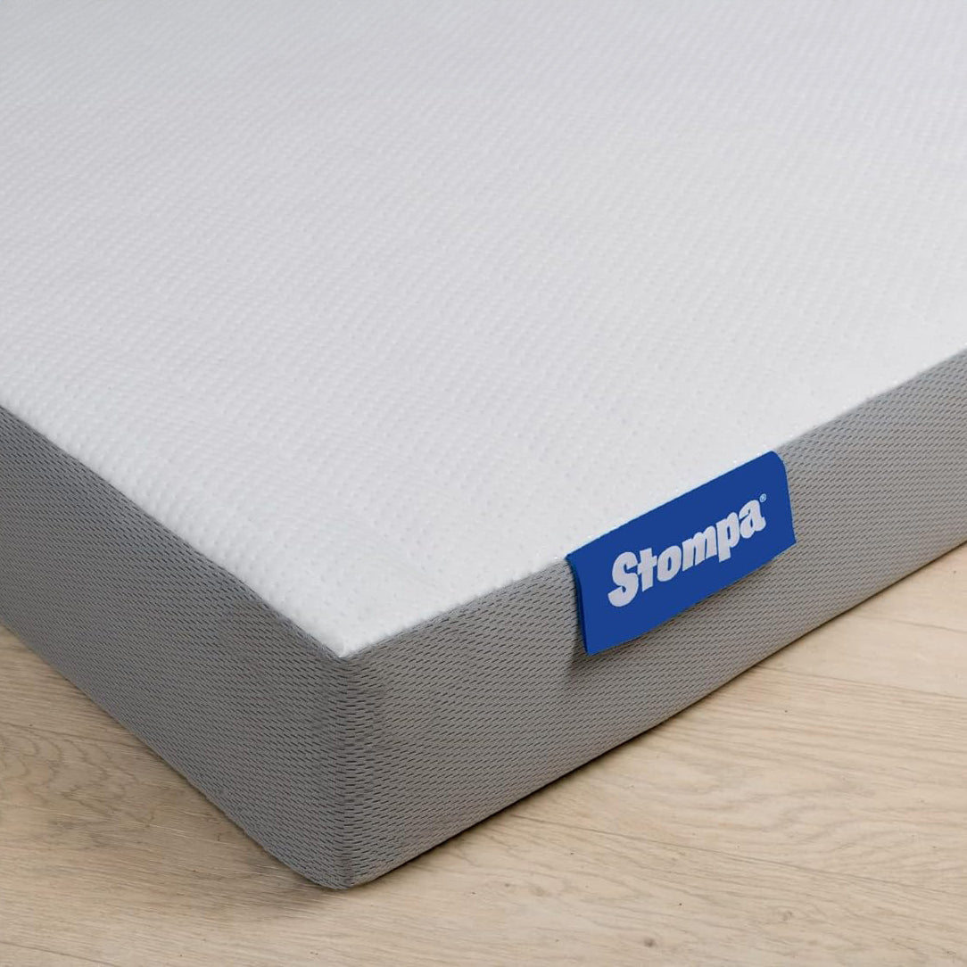 A Stompa brand toddler mattress placed on a wooden floor, showing the side label with the brand name.