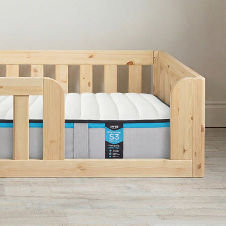 Wooden crib with a mattress labeled 'S3' on a wooden floor.